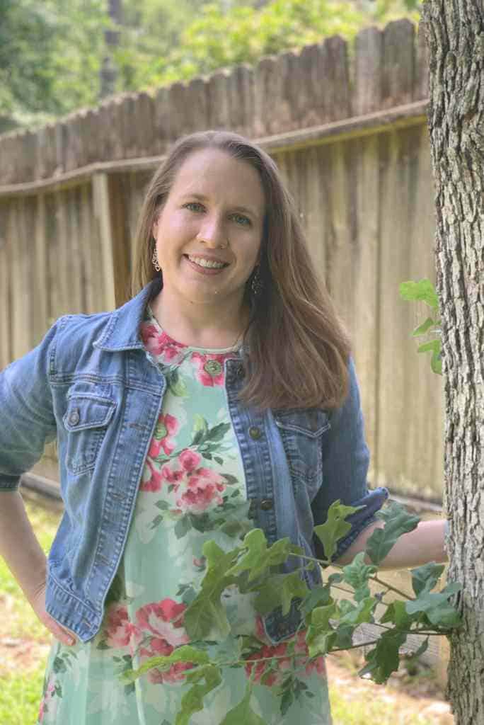 Woman standing in front of fence by tree