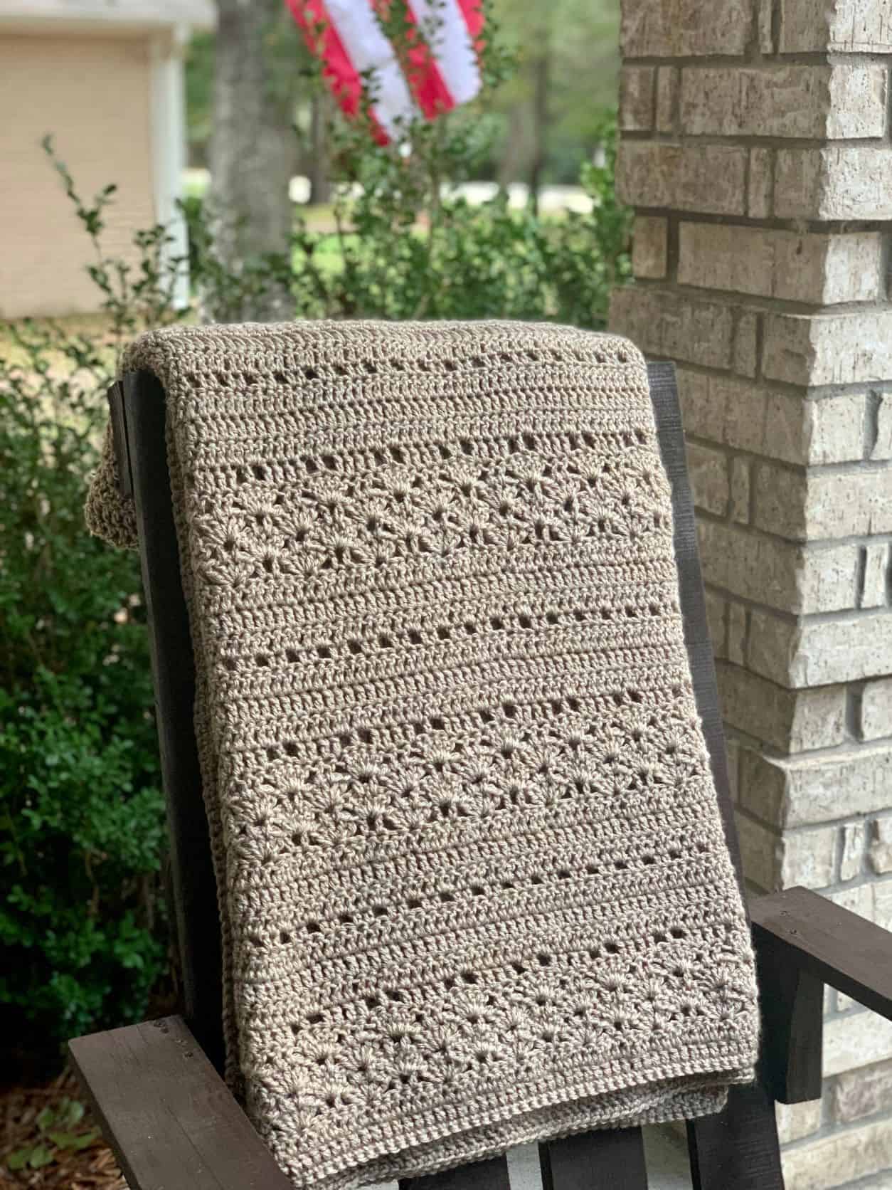rustic throw blanket hung over back of outdoor chair on porch