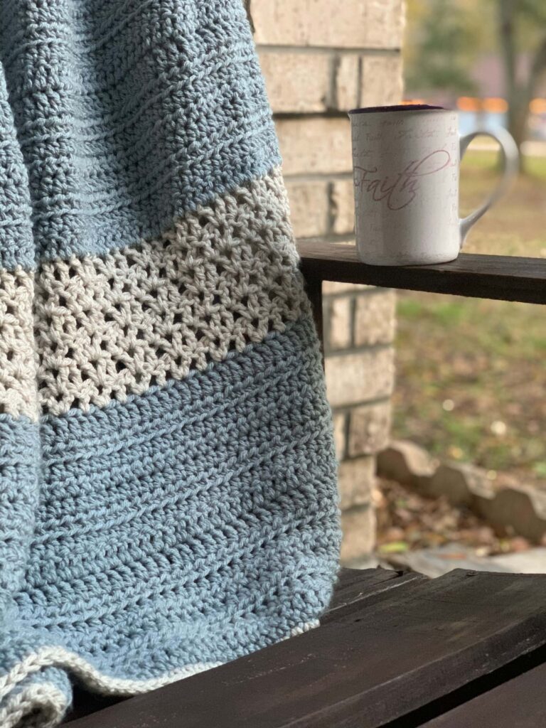 lightly textured blue and gray blanket on outdoor chair with coffee cup