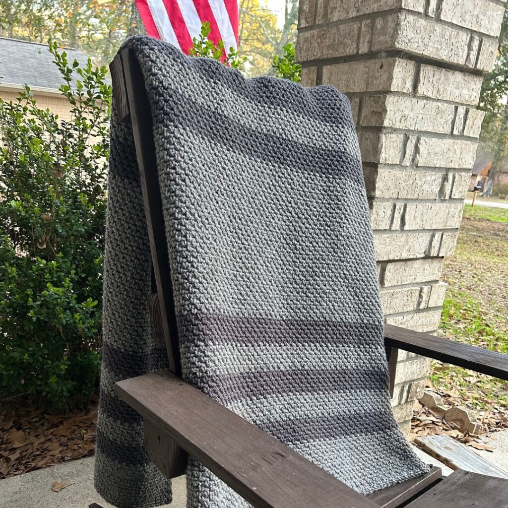 striped gray blanket draped across back of outdoor chair.