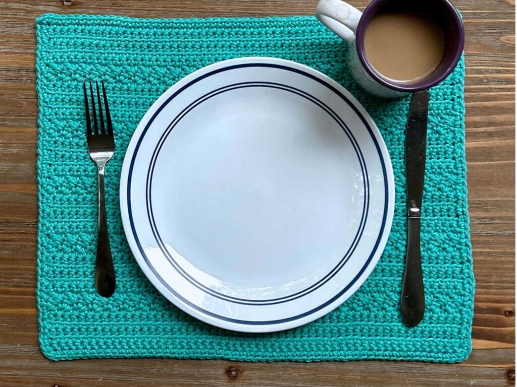 plate, untensils, and cup of coffee on a teal placemat