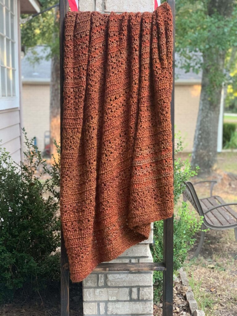 chunky crochet throw blanket on an outdoor blanket ladder