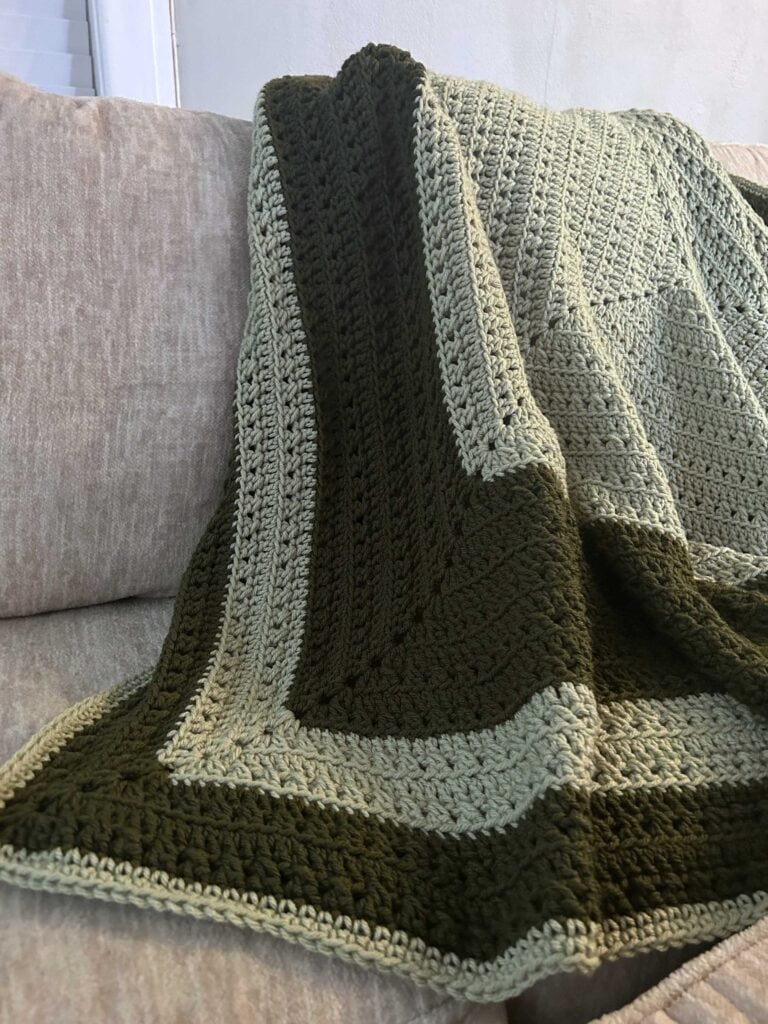 square crochet throw blanket draped over couch