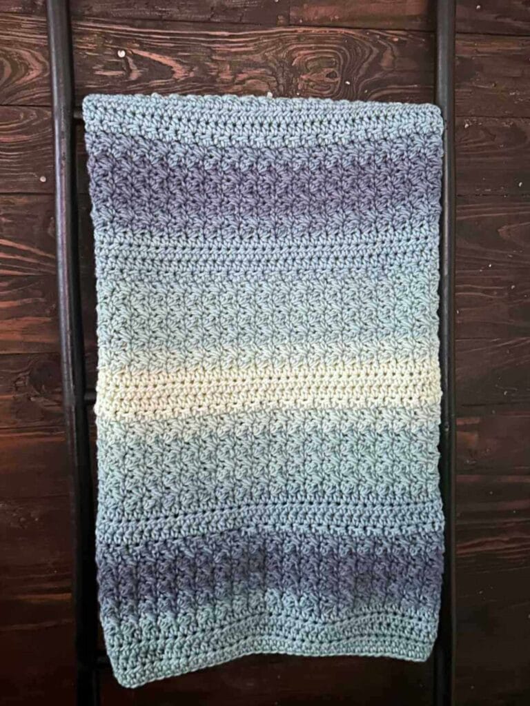 quick and easy crochet baby blanket on wooden blanket ladder leaned up against shiplap wall