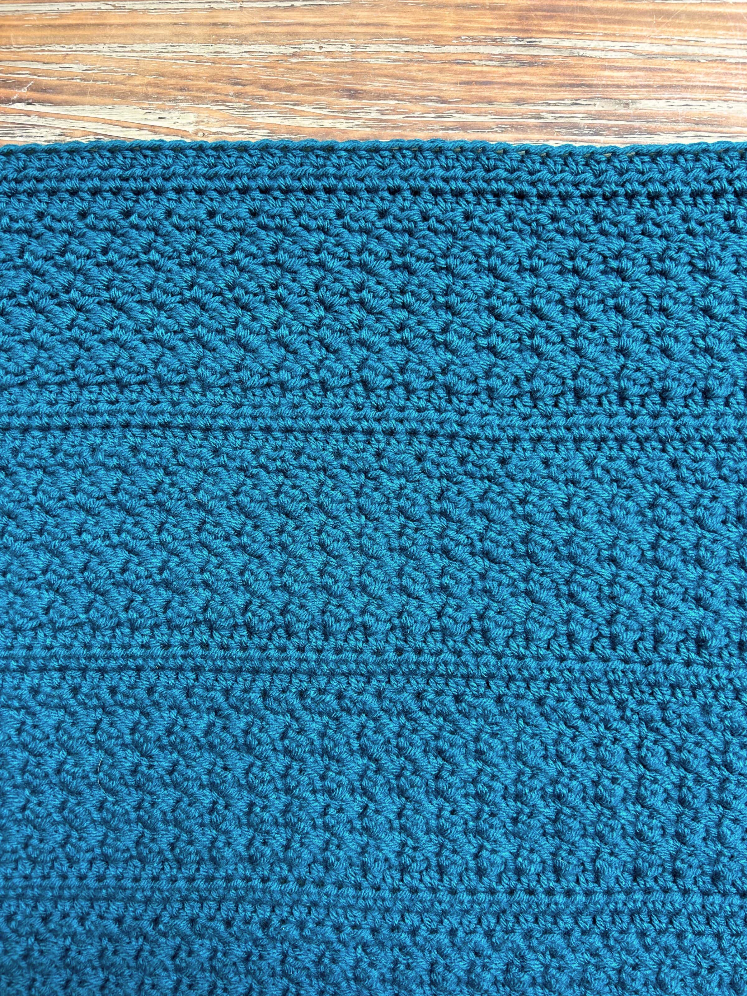 close up of crochet blanket stitches on wooden background