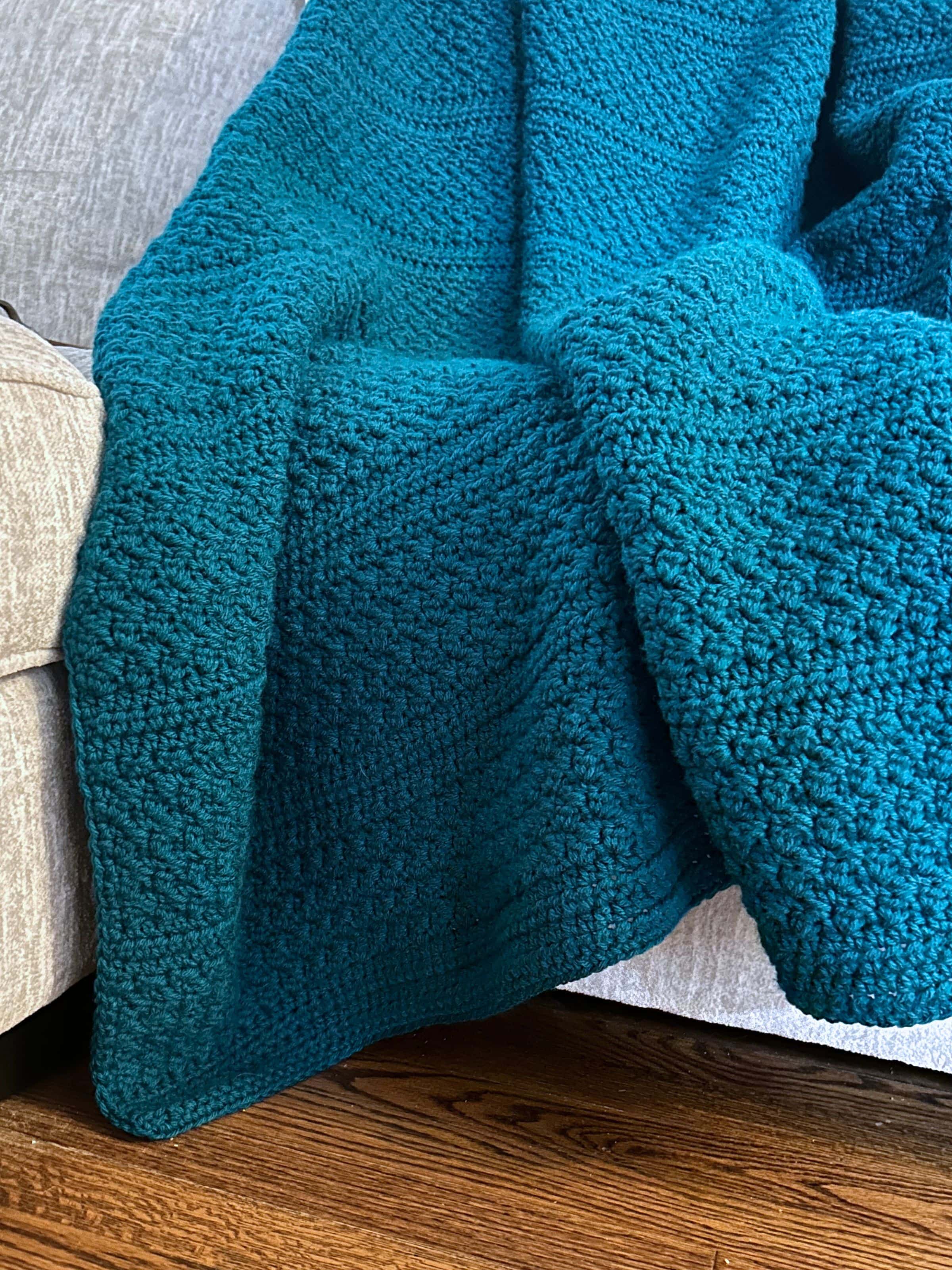 blue crochet throw blanket on gray couch