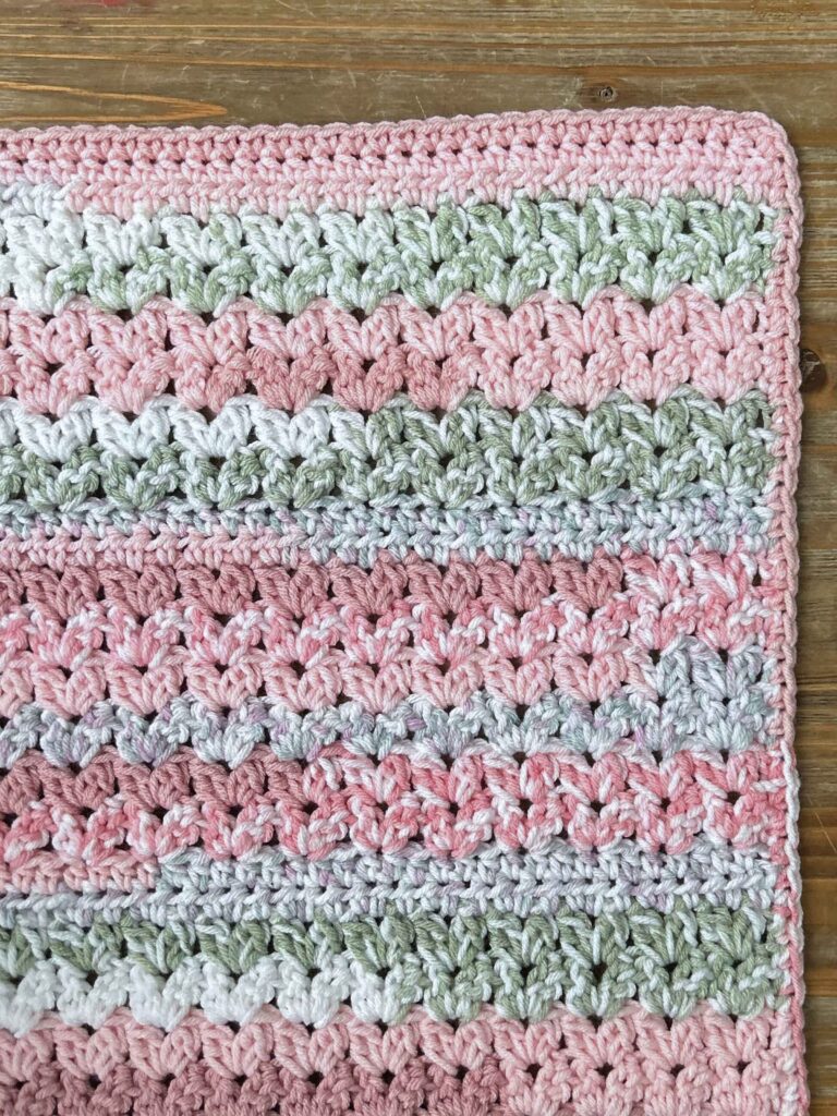 easy baby blanket crochet project with cluster v-stitches using pink, white, and green yarn