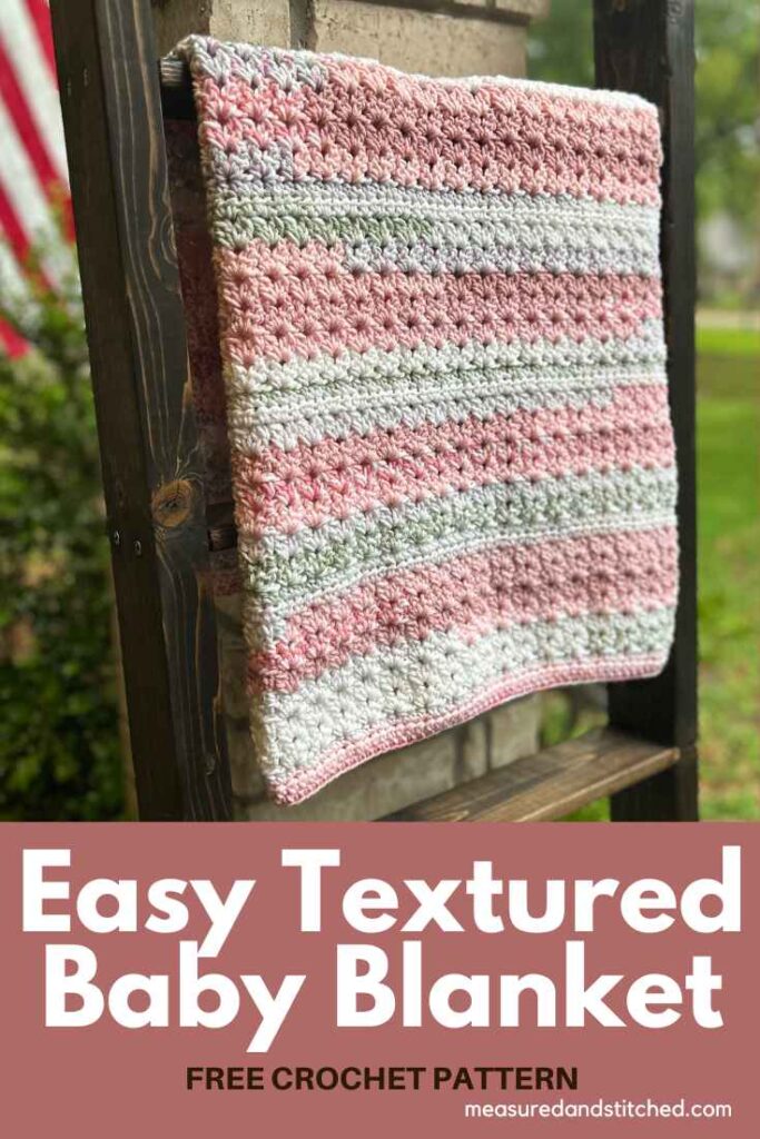Easy Crochet Baby Blanket with cluster v-stitches made with pink, white, and green yarn on blanket ladder, overlay text says "Easy textured baby blanket, www.measuredandstitched.com, Free Crochet Pattern"