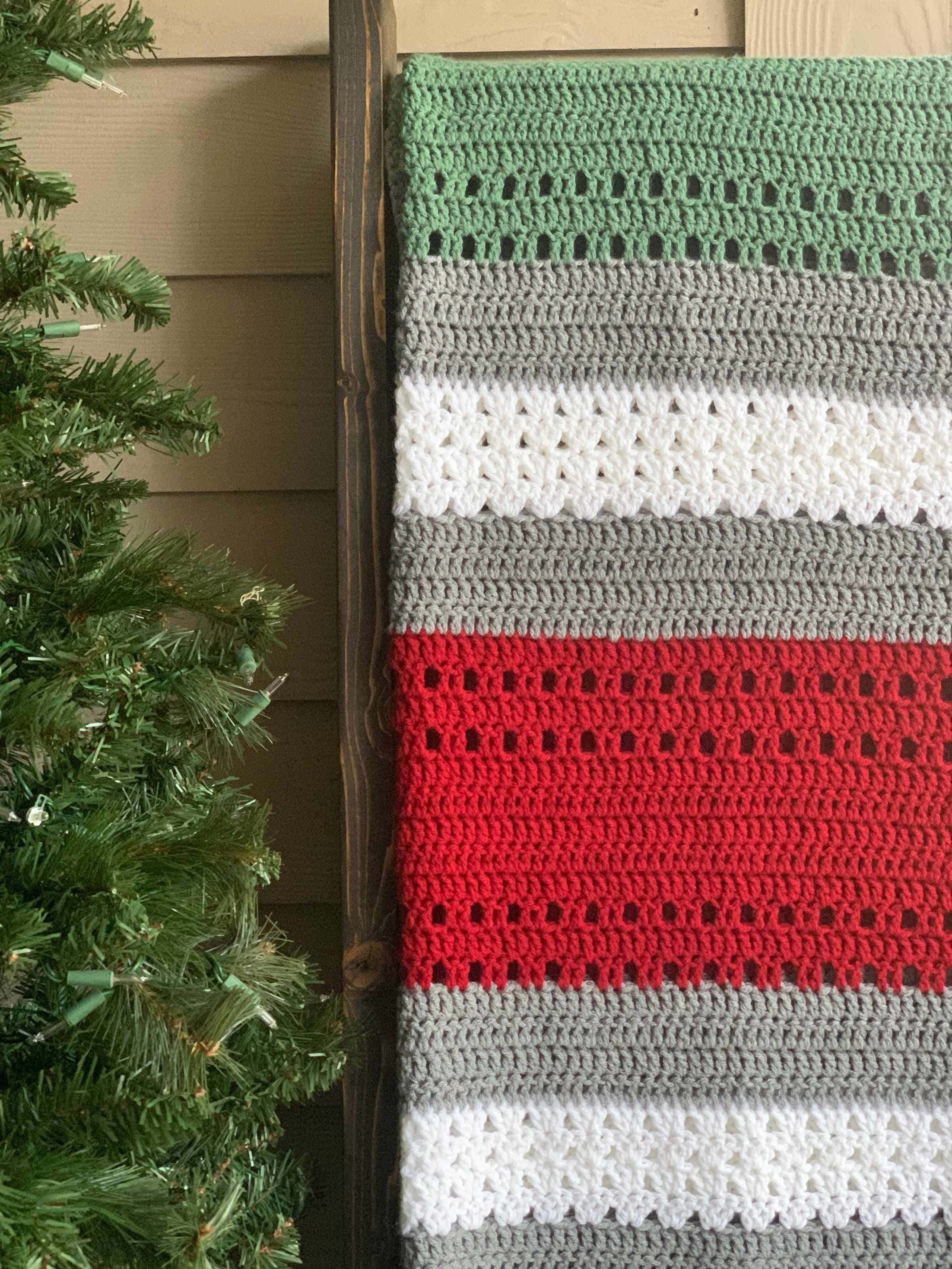 crochet Christmas throw blanket on blanket ladder near evergreen tree
