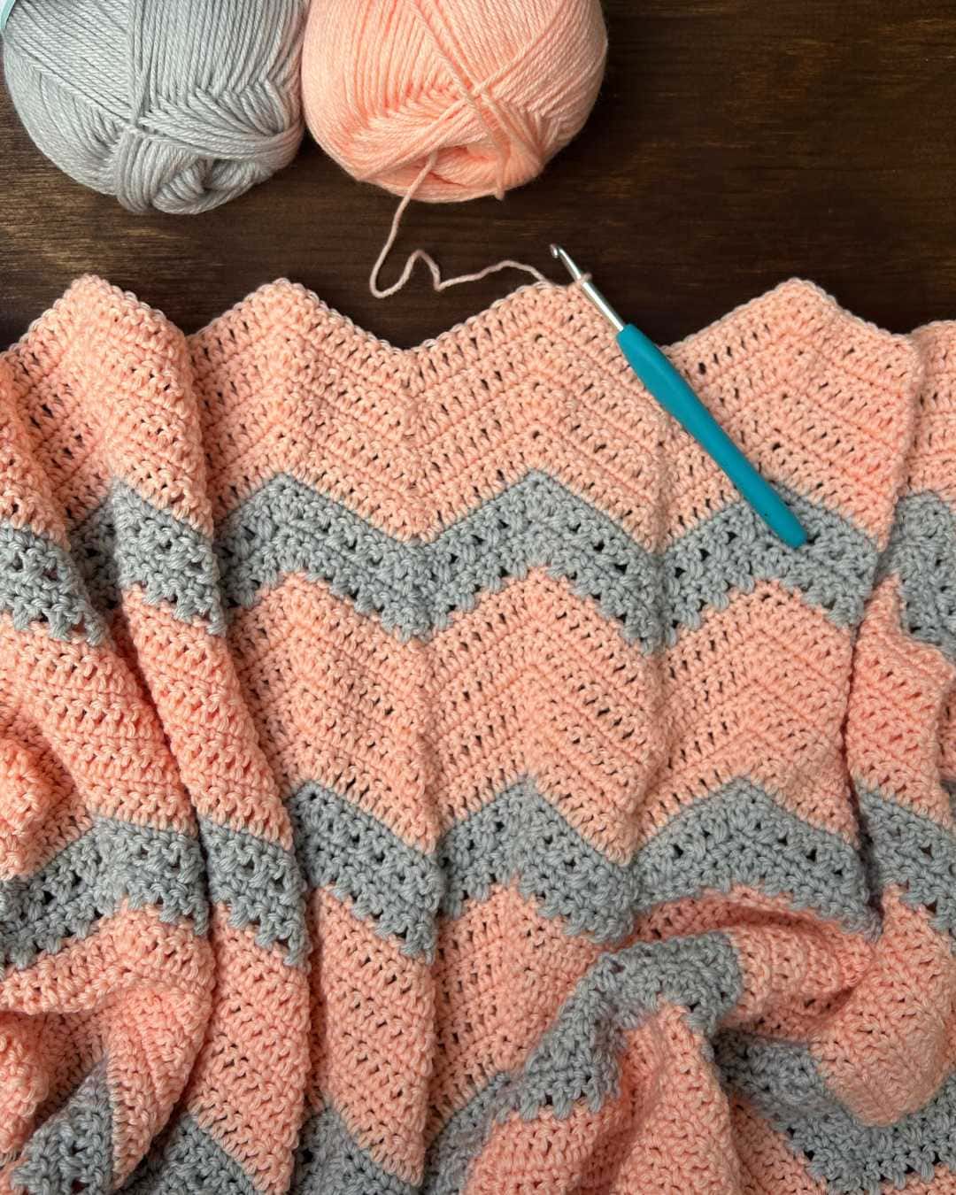 chevron baby blanket work in progress with yarn and crochet hook