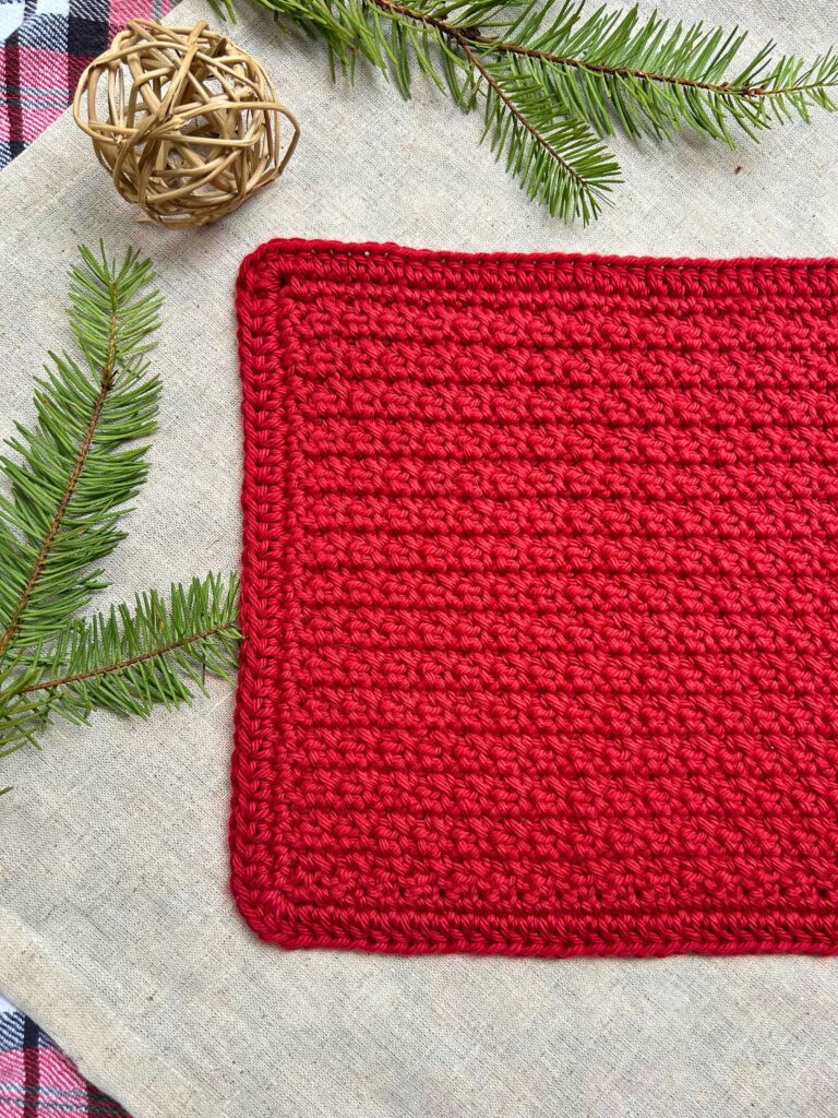 red crocheted dishcloth with winter decor in background