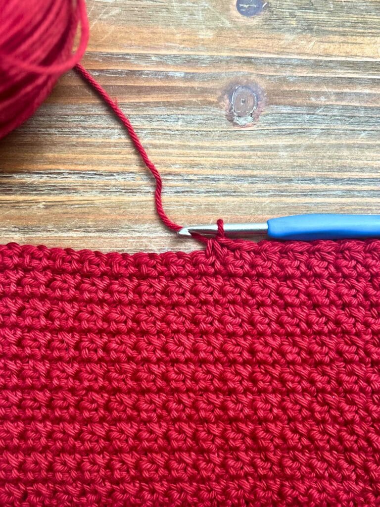 crochet project with red yarn and crochet hook