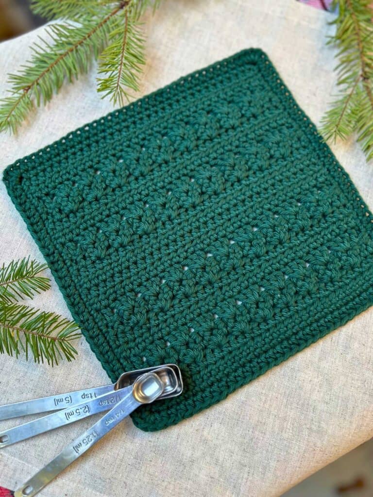 green crochet dishcloth with measuring spoons