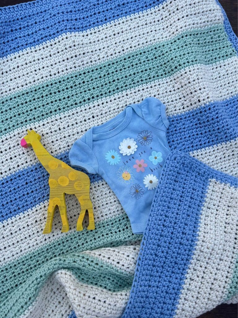 easy striped baby blanket with baby clothes and toys