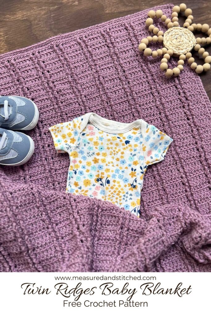 baby blanket with textured ribbing and baby items, overlay text reads "www.measuredandstitched.com, Twin Ridges Baby Blanket, Free Crochet Pattern"