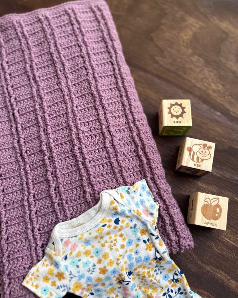 purple crochet baby blanket with baby items