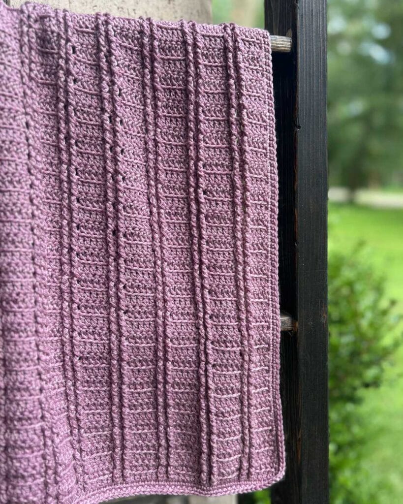 purple crochet baby blanket on outdoor blanket ladder
