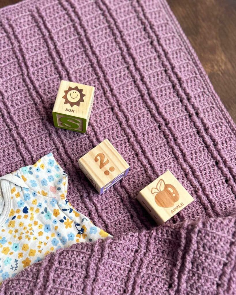 crochet baby blanket with textured ribbing and baby items