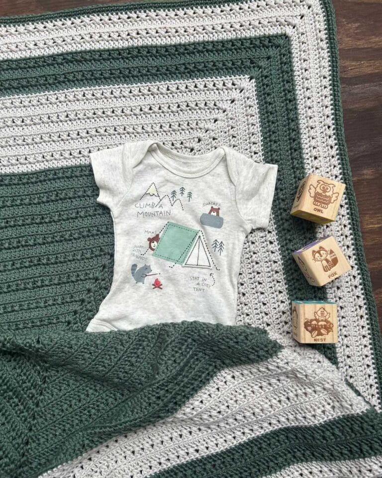 A baby blanket with a t - shirt and wooden blocks.