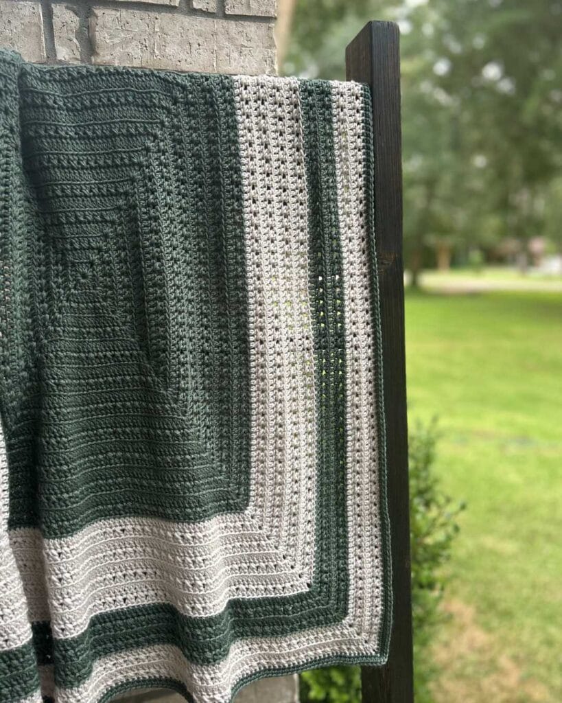 A green and white crocheted blanket on blanket ladder