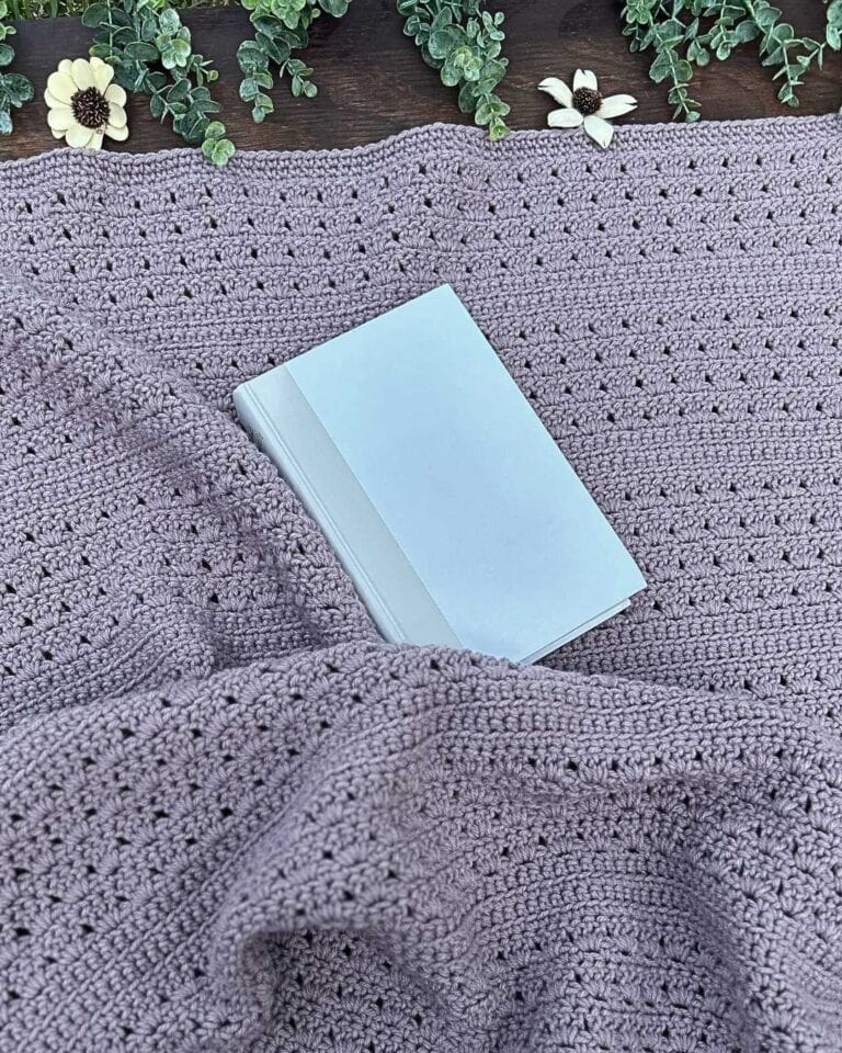 purple crochet throw blanket with white book and greenery