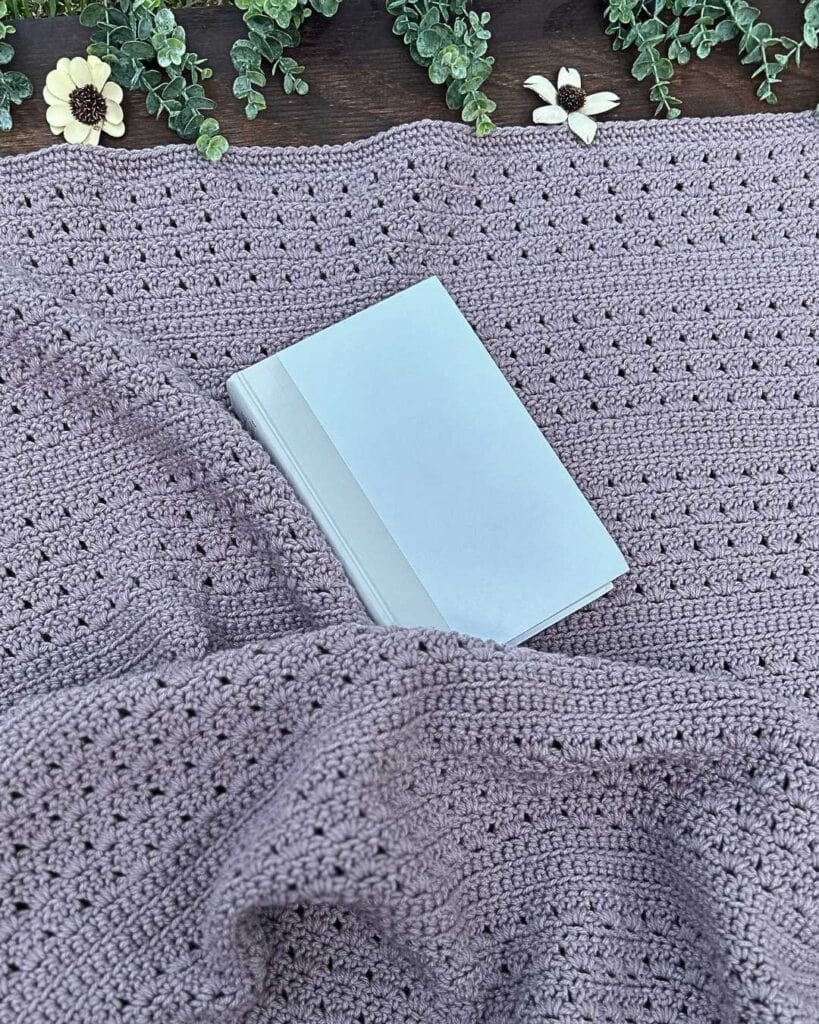 purple crochet throw blanket with white book and greenery